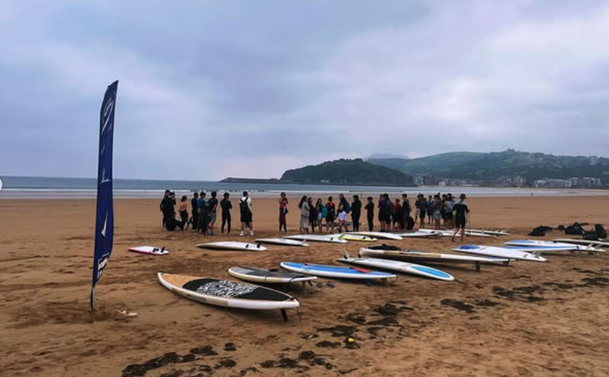 Grupo de Surf & Grind Gasteiz en la playa, con las tablas alineadas en la arena antes de entrar al agua
